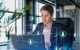 handsome businessman in suit at workplace working with laptop to hire new employees for international business consulting. hr, social media hologram icons over office background